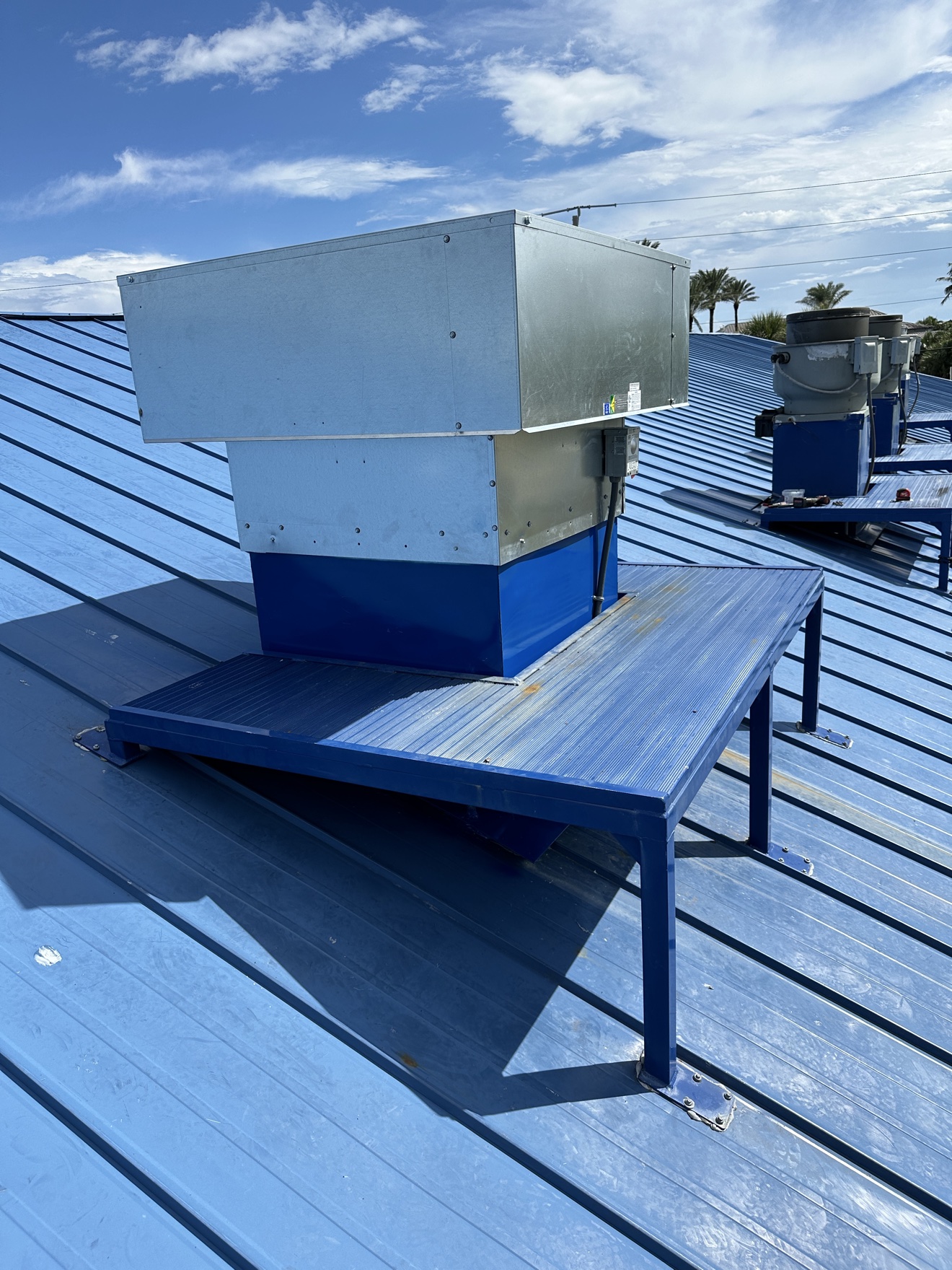 Close-up of a rooftop HVAC unit on a blue metal roof