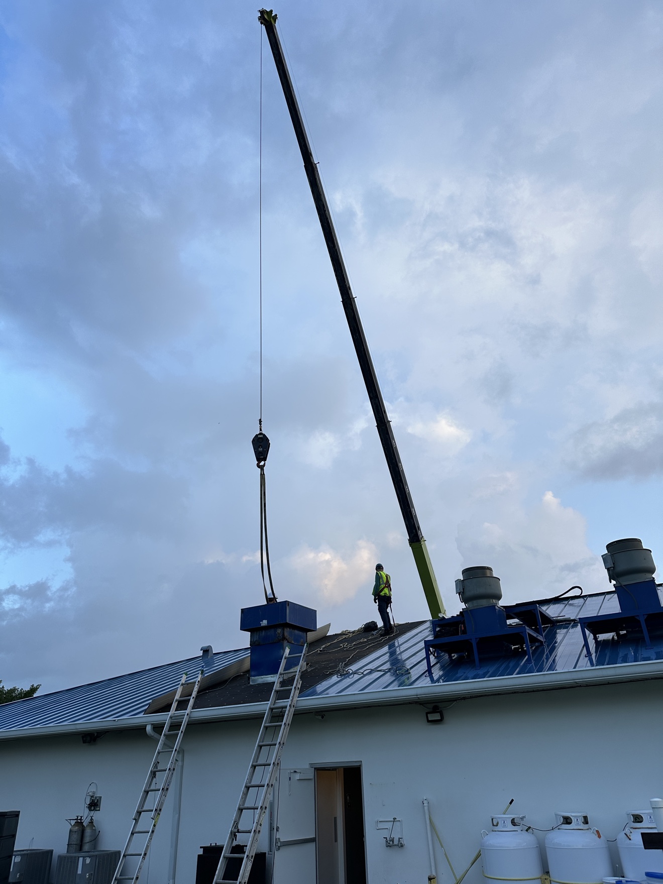 Commercial metal roof with crane and workers