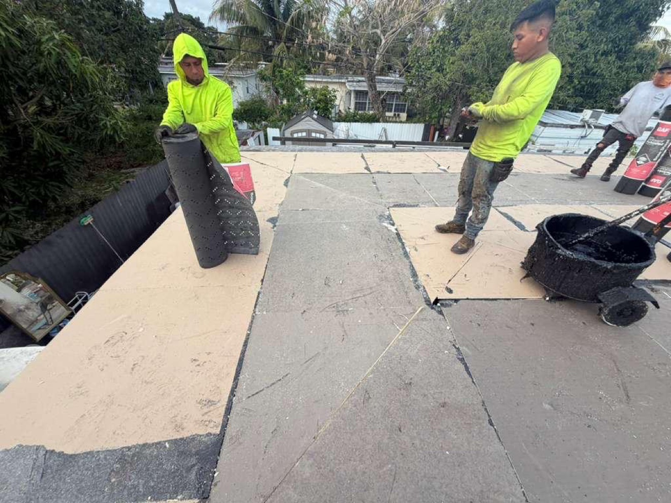 Workers rolling base sheet with hot-mop cart