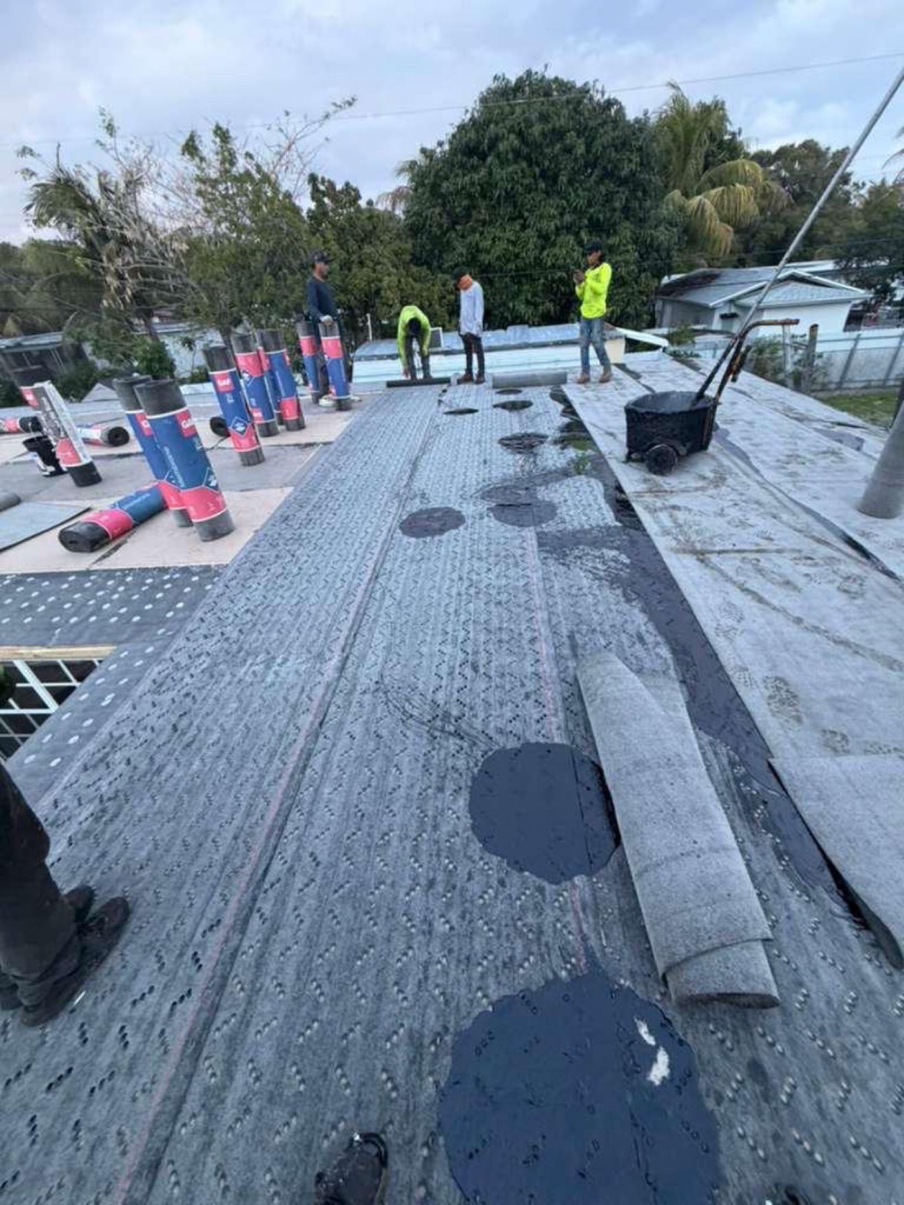 Base sheet with hot-mop cart and GAF rolls, workers on site