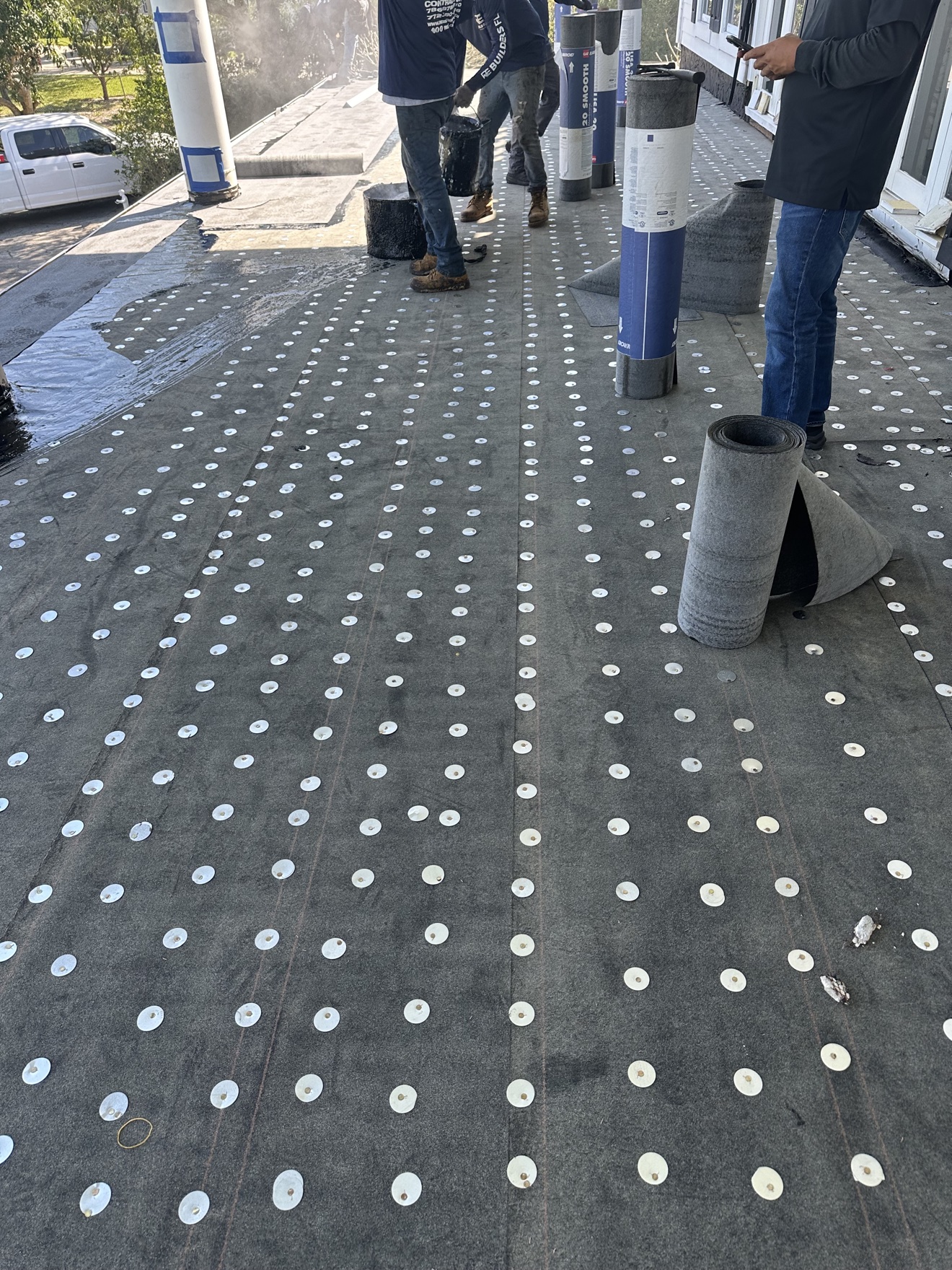 Close-up of base sheet with fastener plates, crew and rolls staged