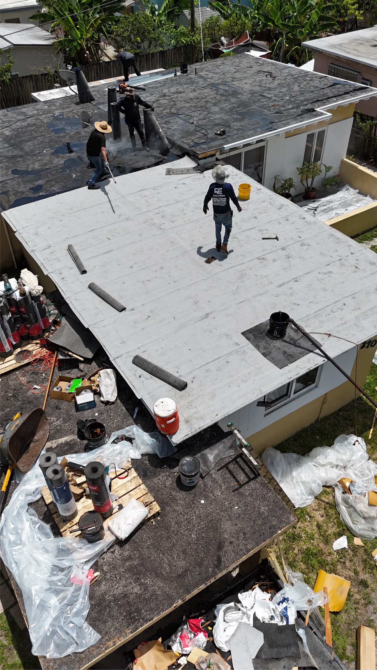 Aerial of a finished flat roof with crew on a black section