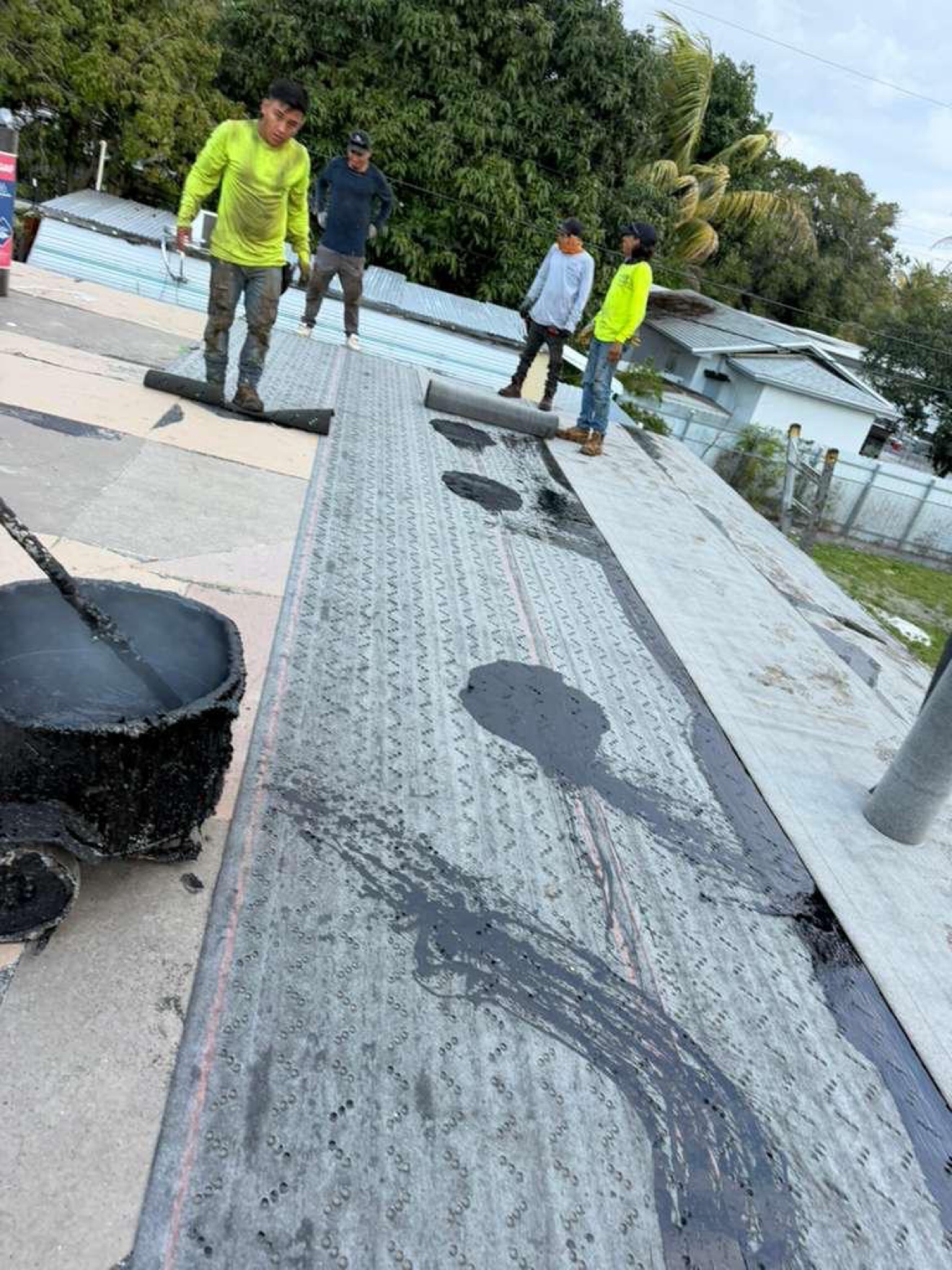 Workers mopping base sheet with hot-mop cart and GAF rolls