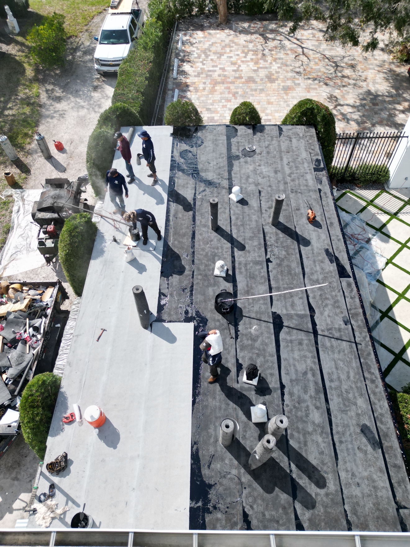 Top-down aerial of crew on a flat roof during cap sheet install