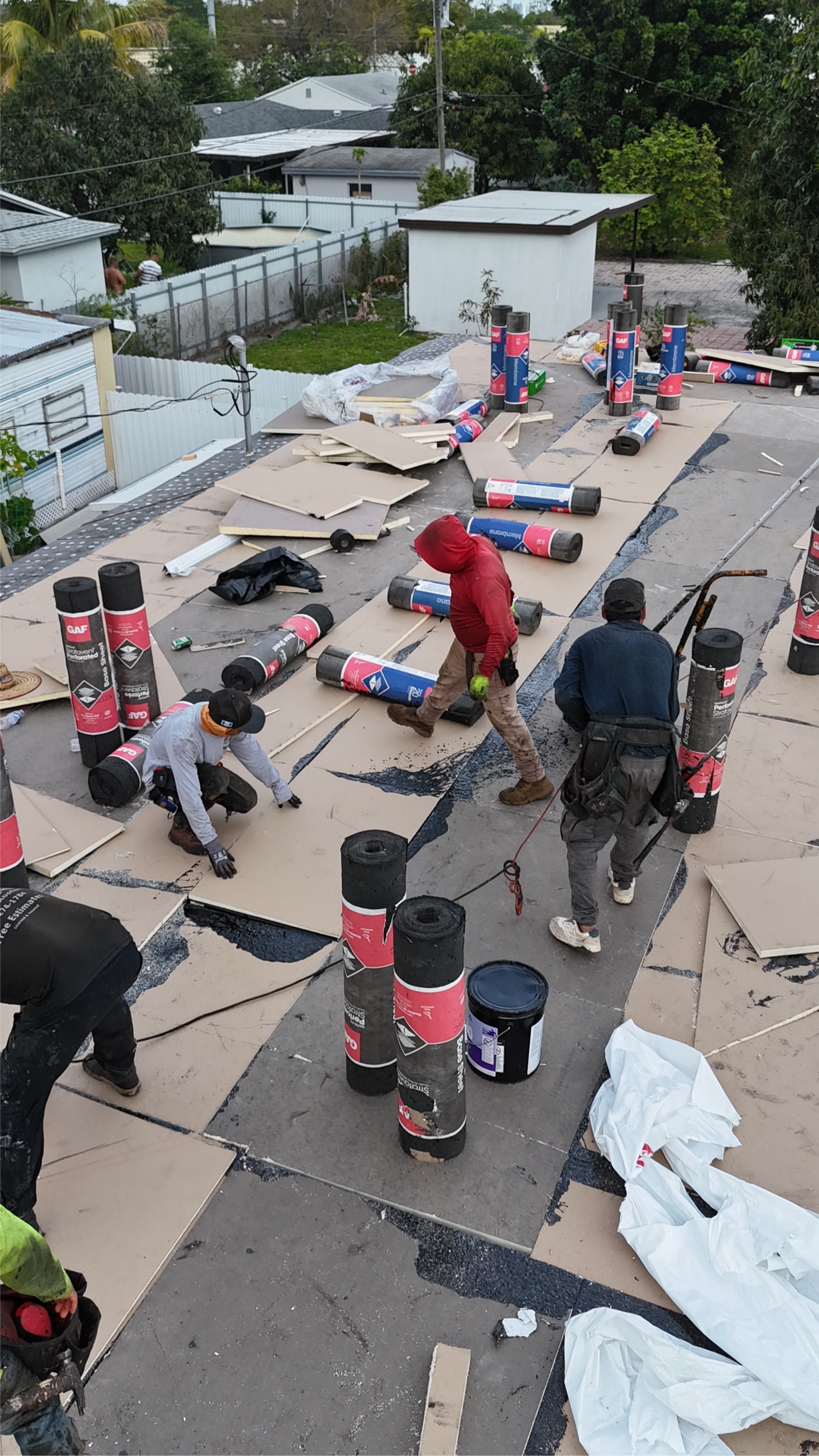 Flat roof with tapered insulation boards and GAF rolls being installed