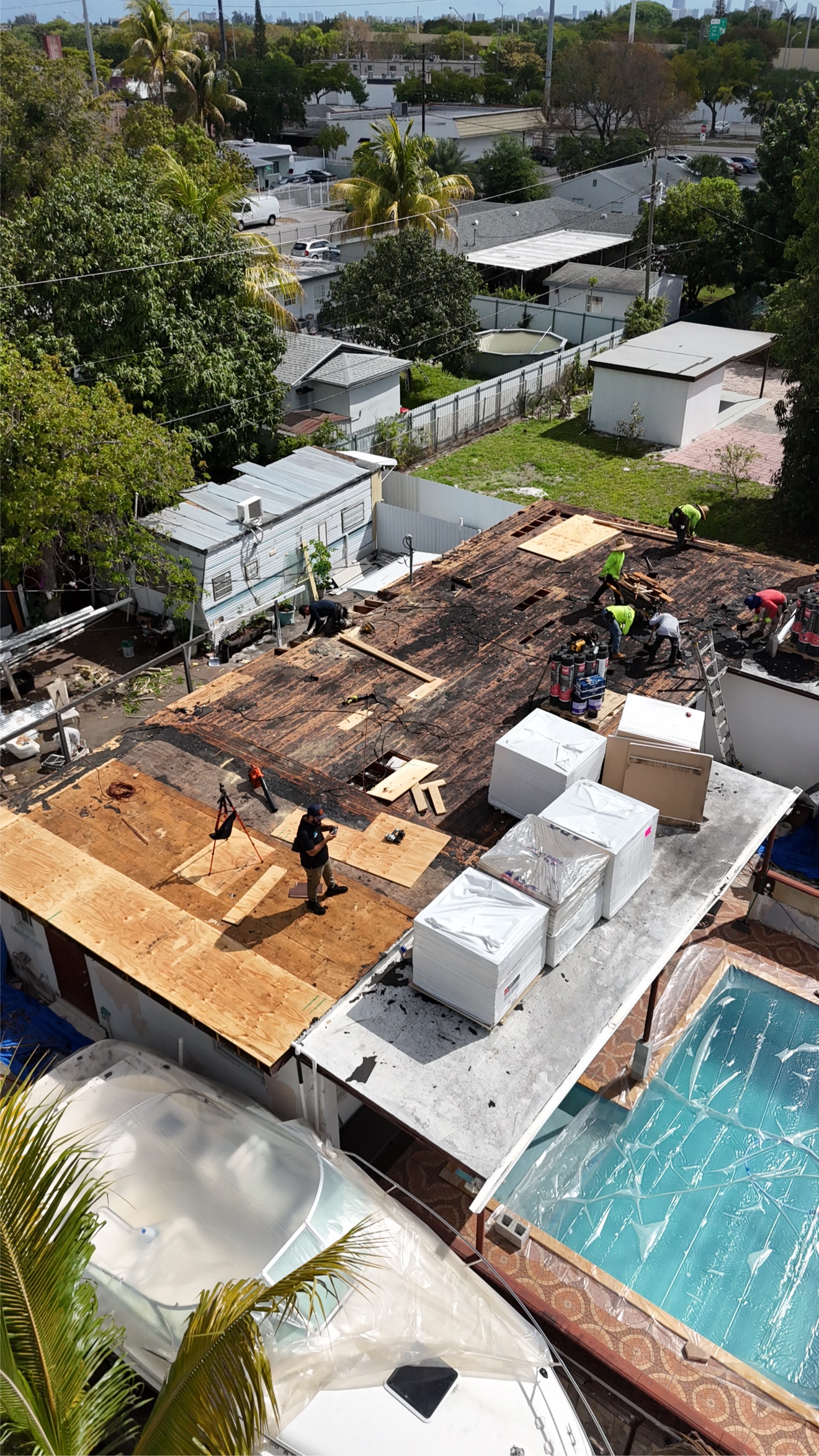 Aerial of flat roof tear-off in progress with crew and materials