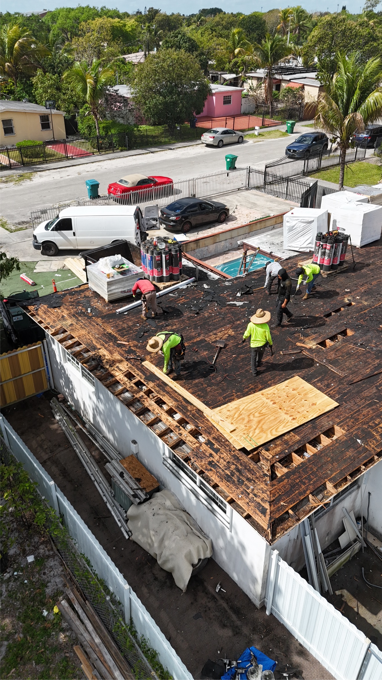 Aerial of crew tearing off a flat roof with foam boards stacked