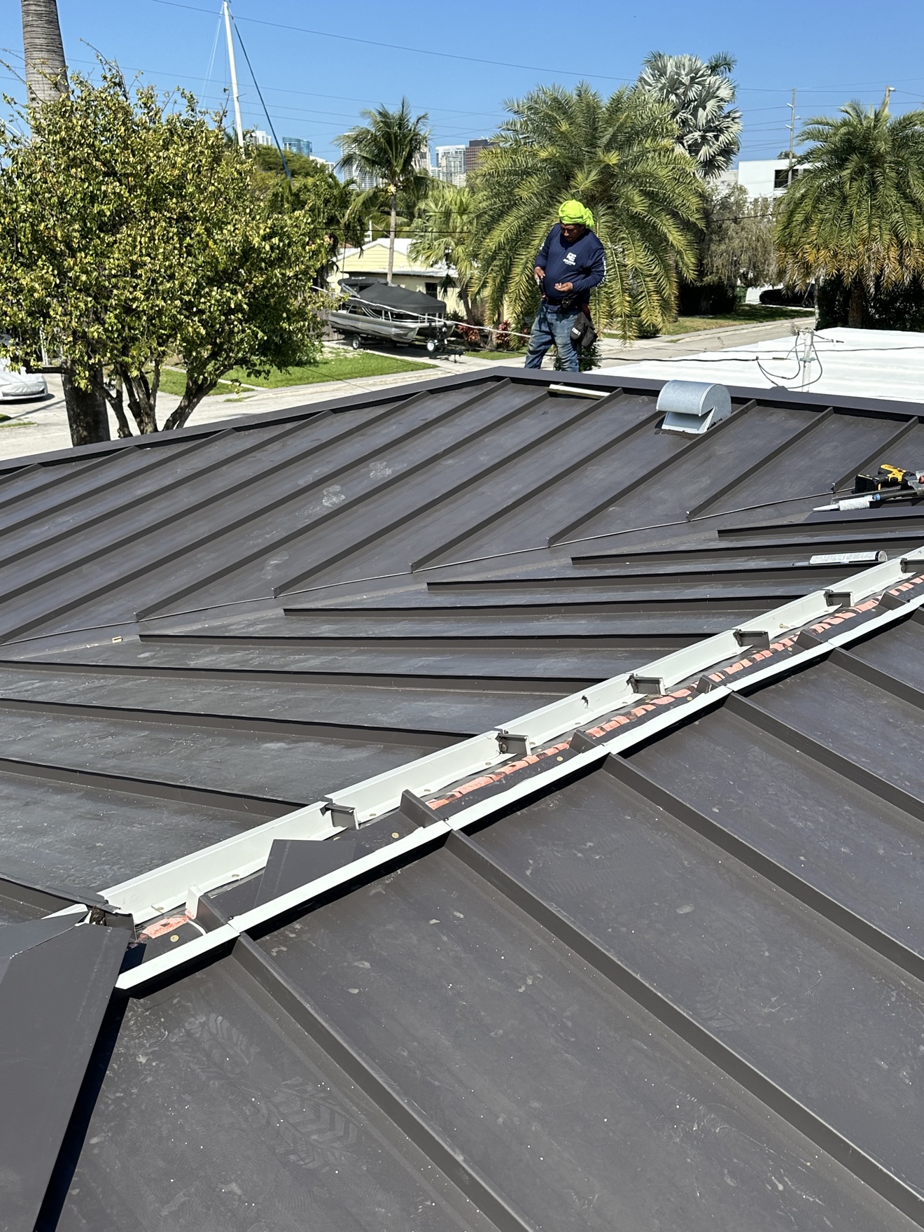 Worker on a new metal roof installing the ridge