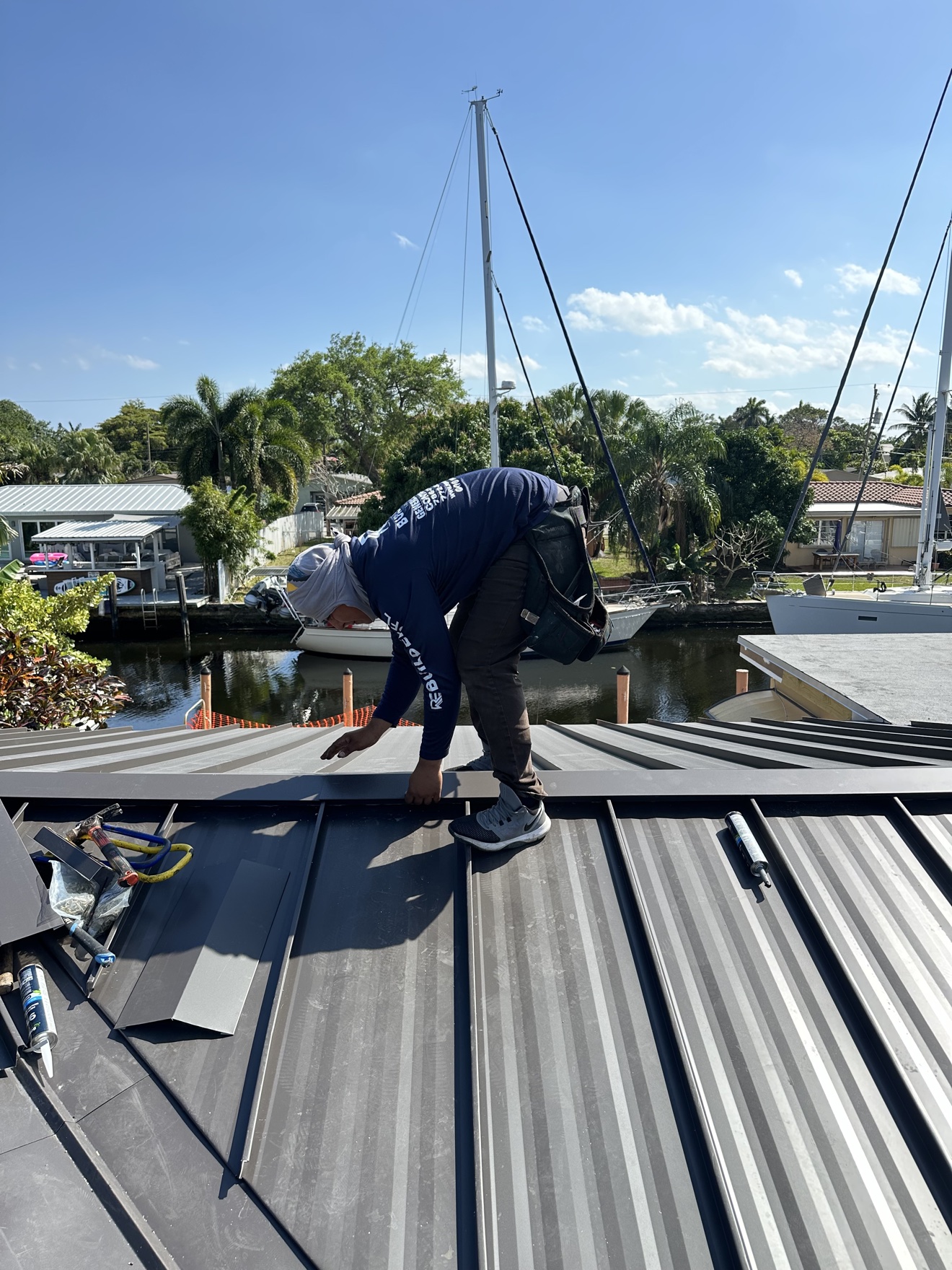 Worker installing metal panels with sailboats behind