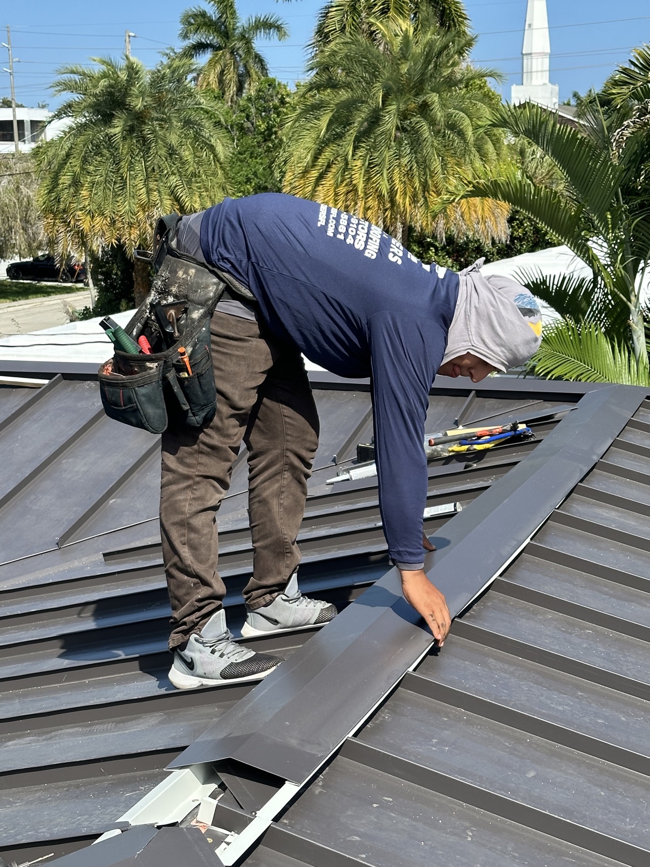 Worker installing the ridge cap on a metal roof