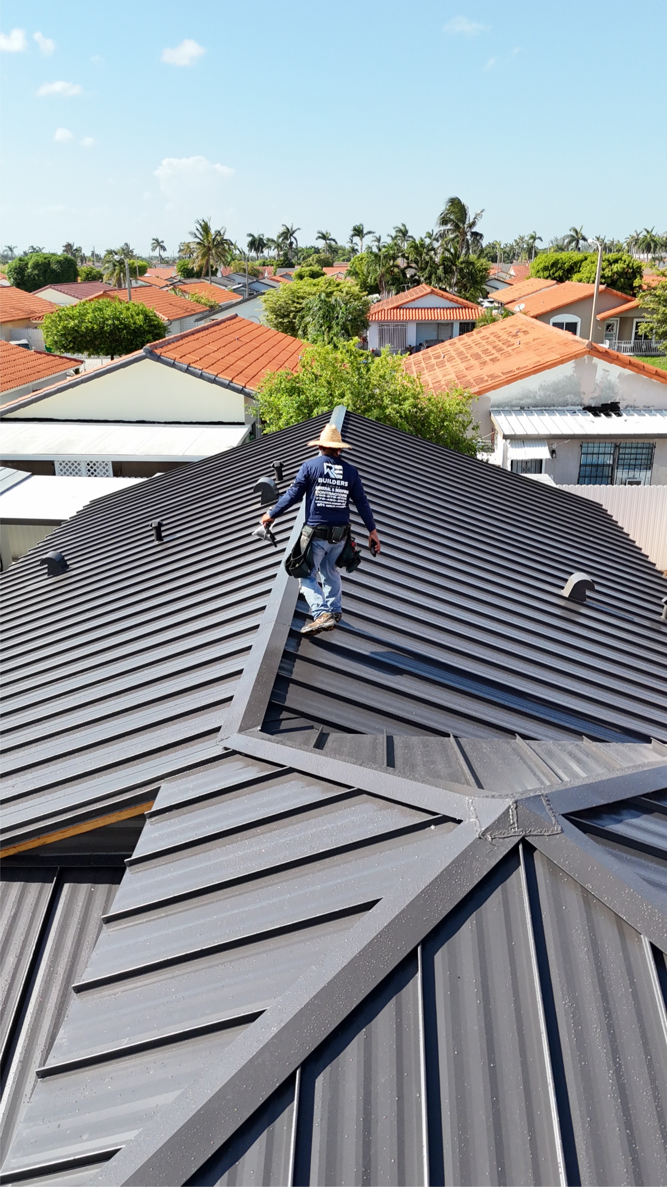 Worker walking the ridge of a standing seam metal roof