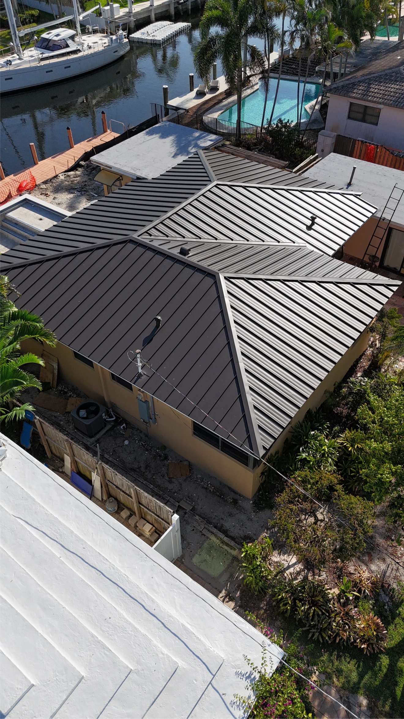 Aerial of finished metal roof on a waterfront home with dock and pool