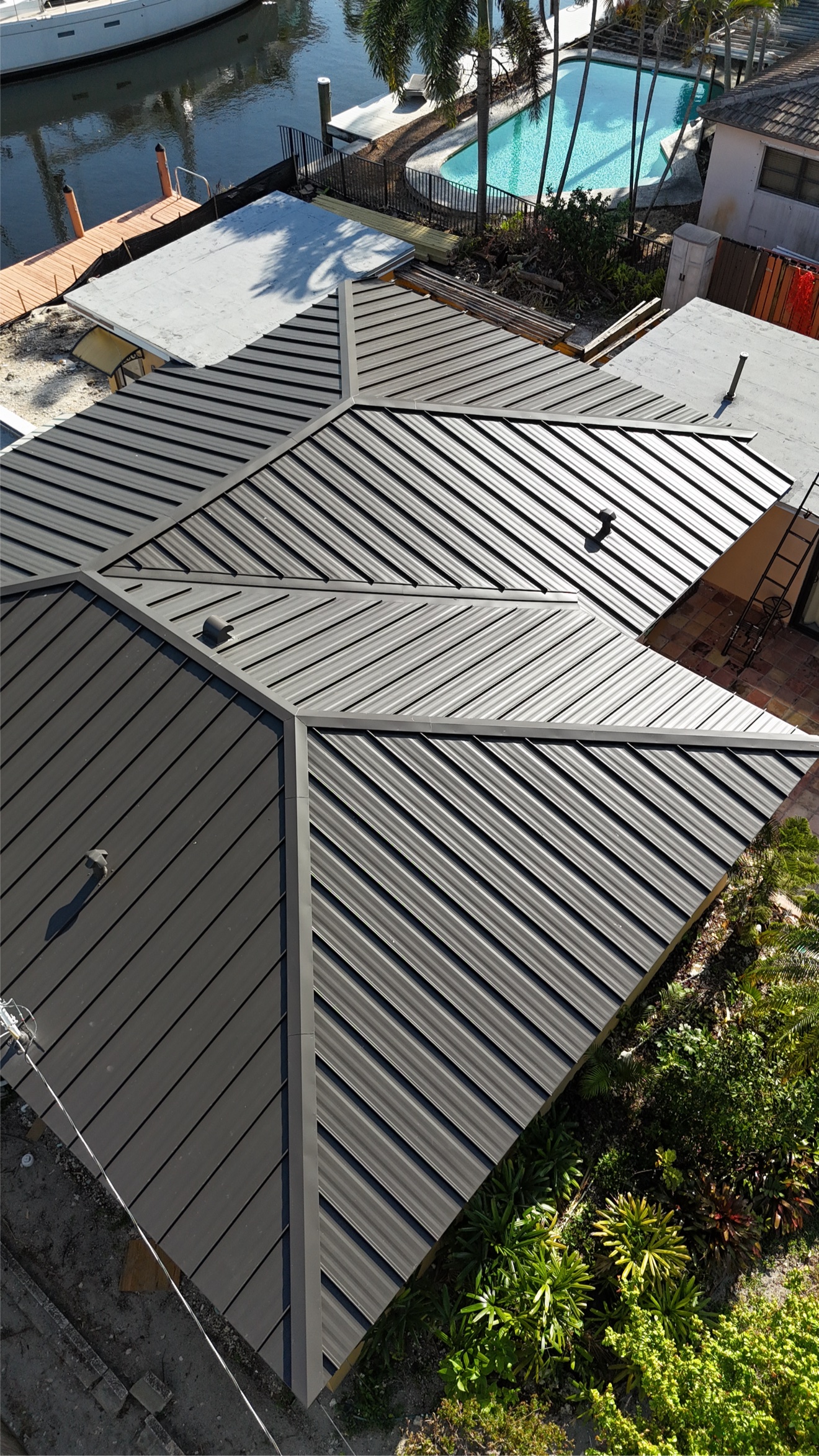 Close aerial of a finished metal roof with pool behind