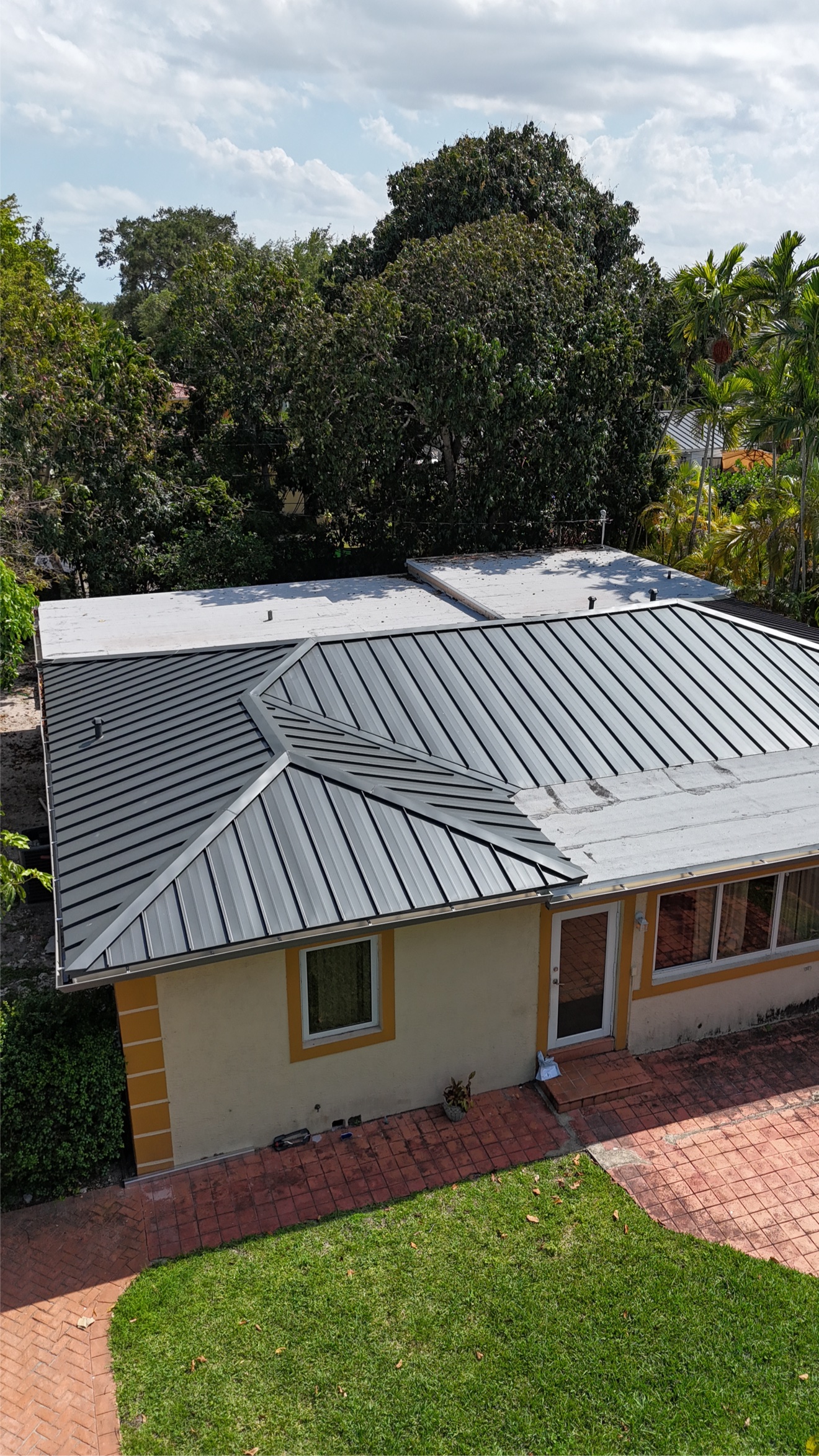 Aerial of a home with new metal roof and flat white sections
