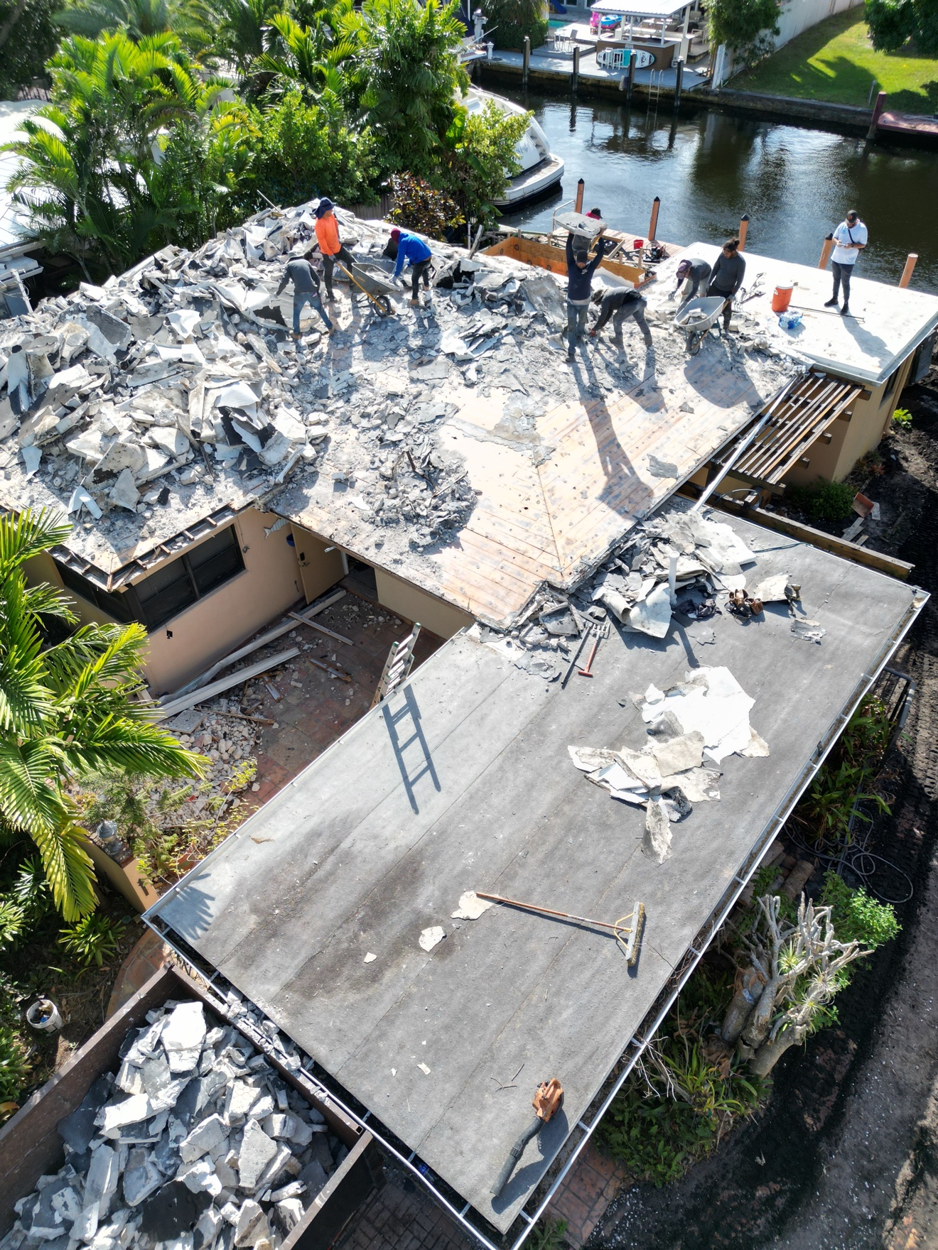 Aerial of crew tearing off the old roof on a waterfront home