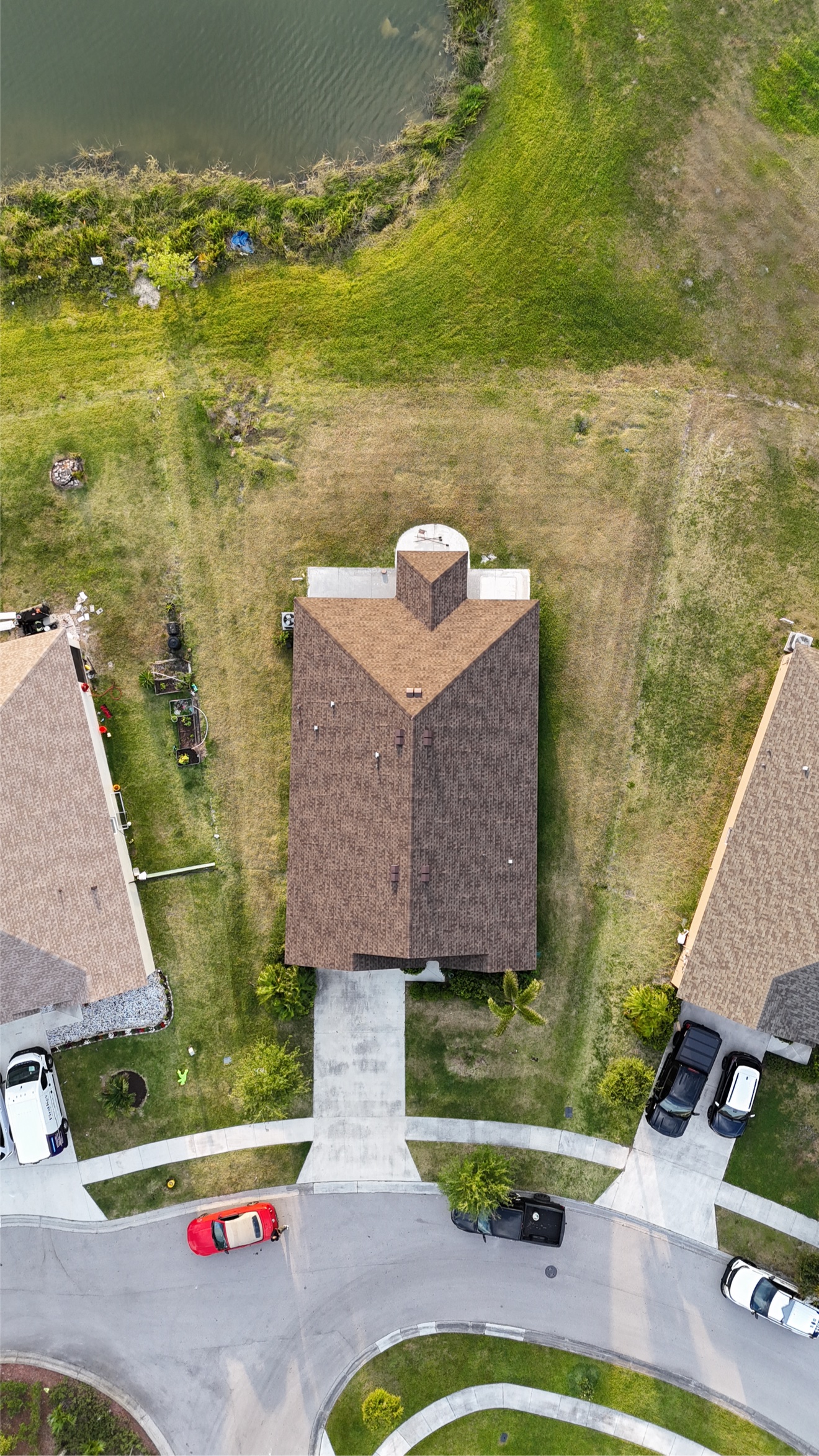 Top-down aerial of a finished shingle roof with lake behind
