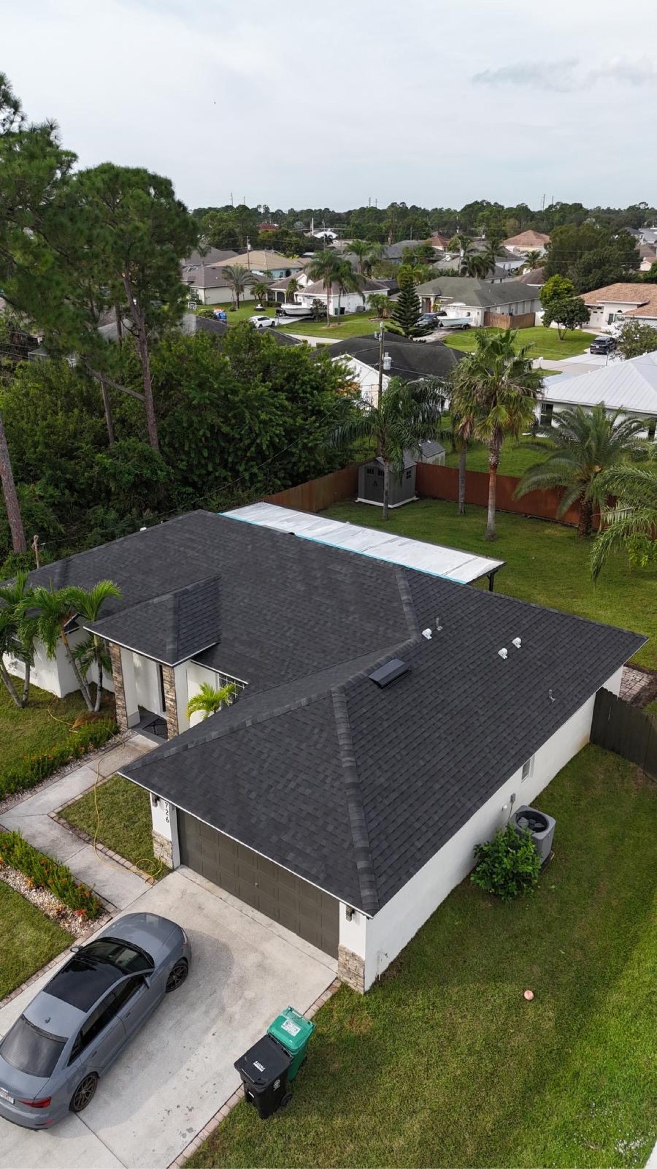 Aerial of a finished dark shingle roof with a lake