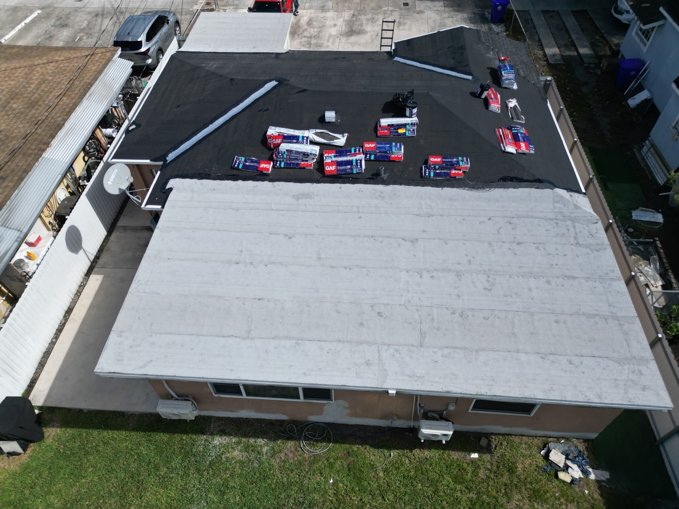 Aerial of a shingle and flat combo roof with materials staged