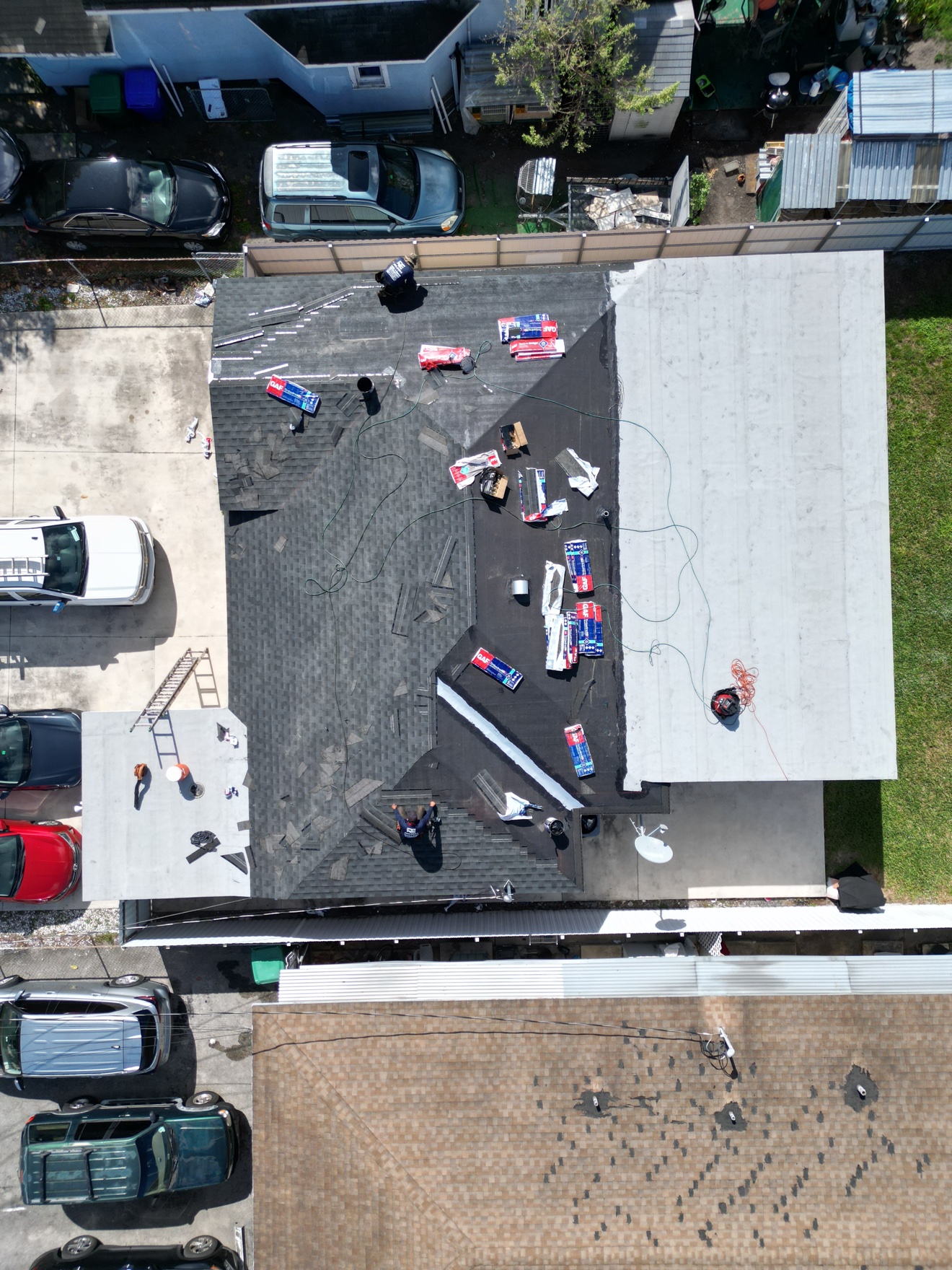 Aerial of shingle tear-off in progress with flat section beside