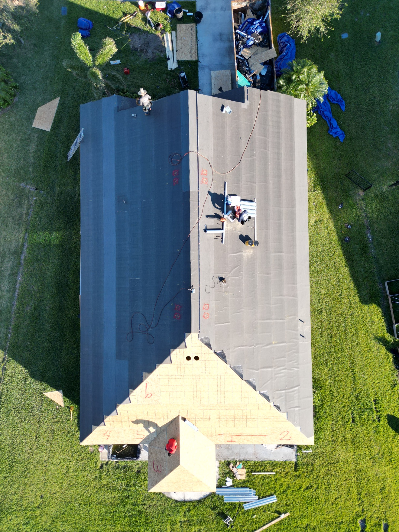 Aerial of shingle install with underlayment and workers