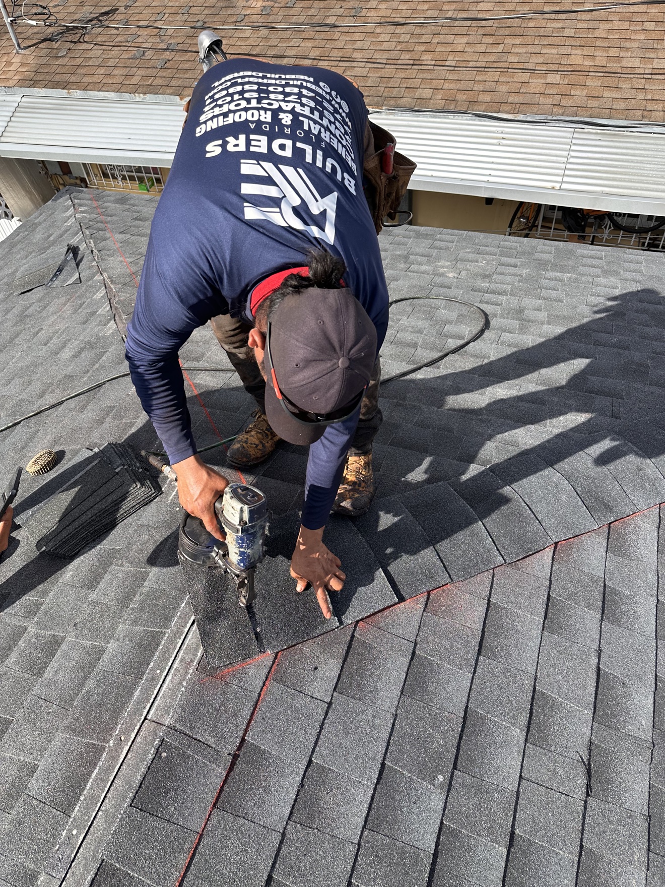Close-up of RE Builders worker nailing shingles