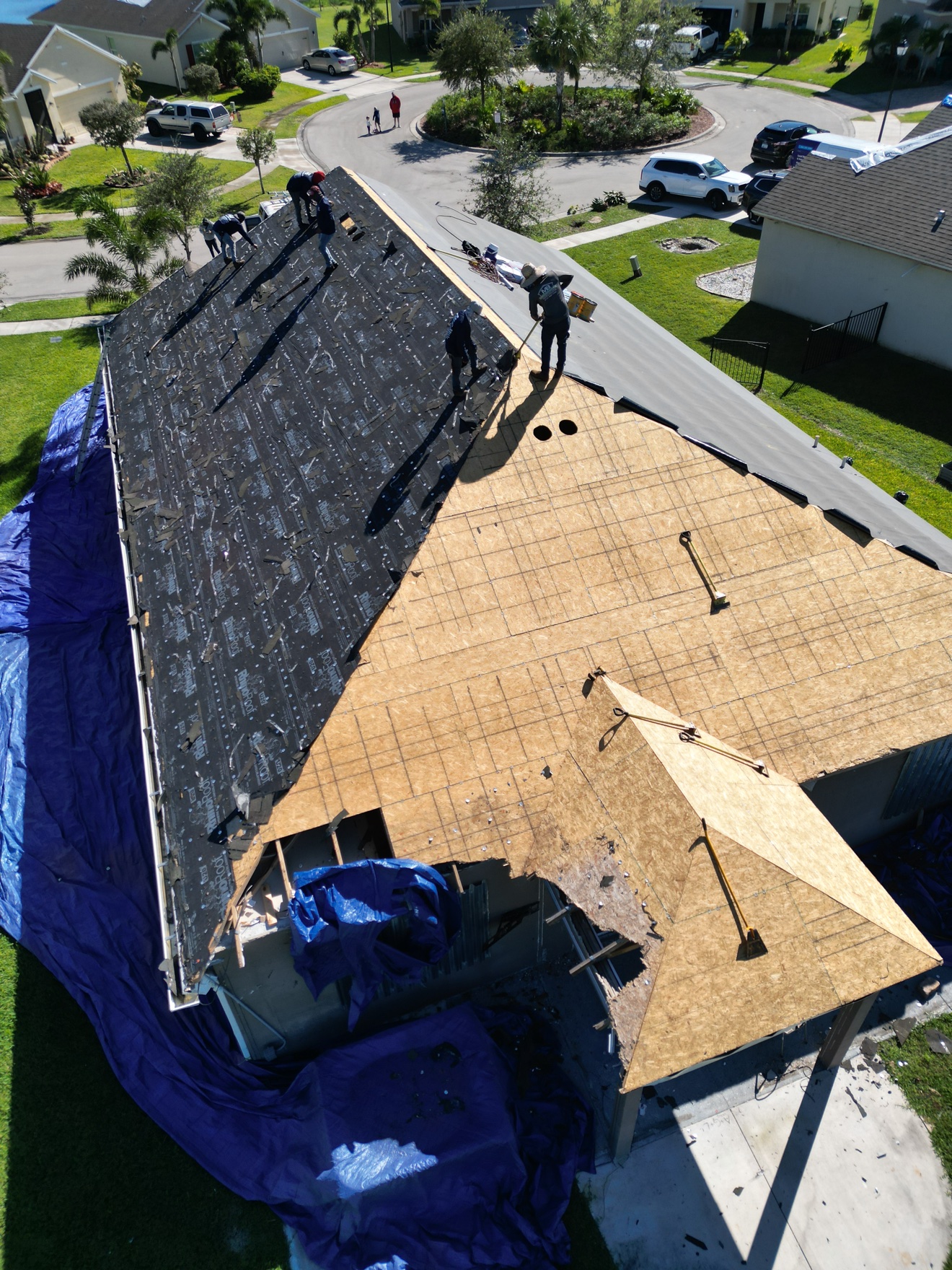 Aerial of shingle tear-off in progress, crew on OSB deck
