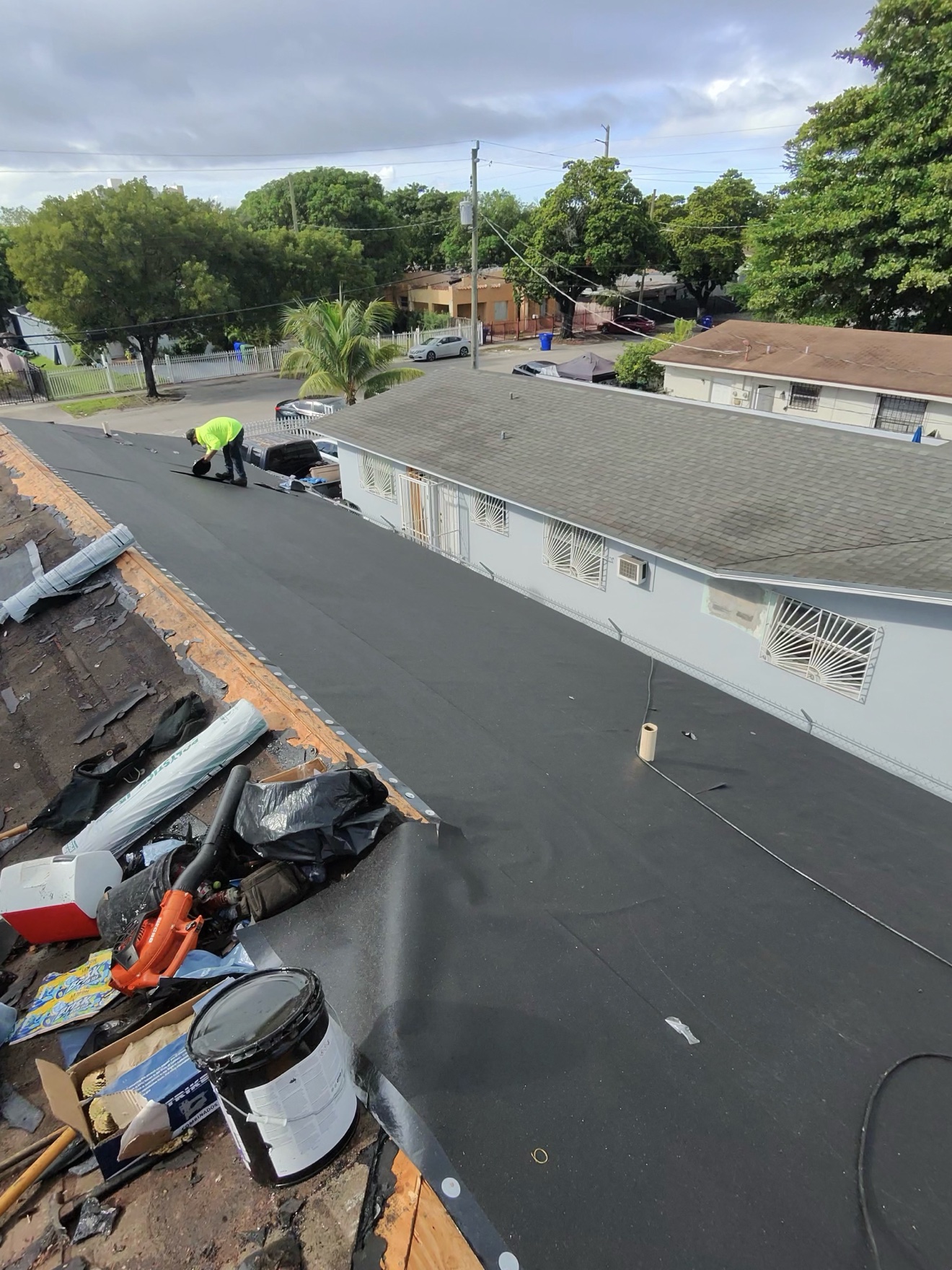 Worker installing underlayment on a shingle roof tear-off