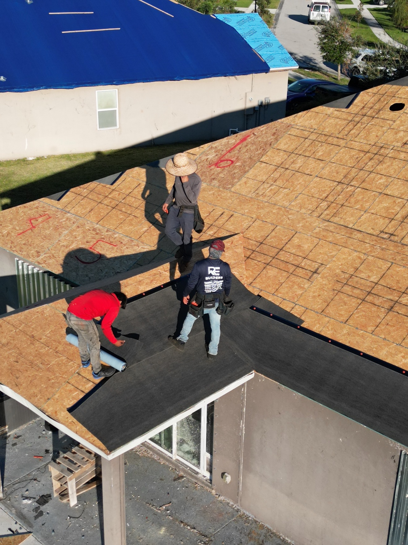 RE Builders crew on OSB deck installing underlayment