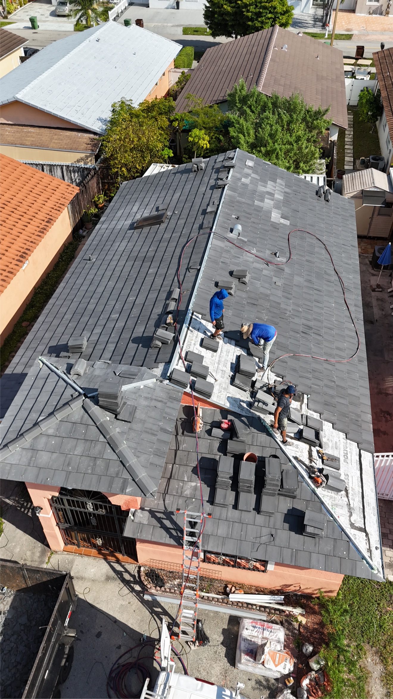 Aerial of crew installing tiles near the ridge