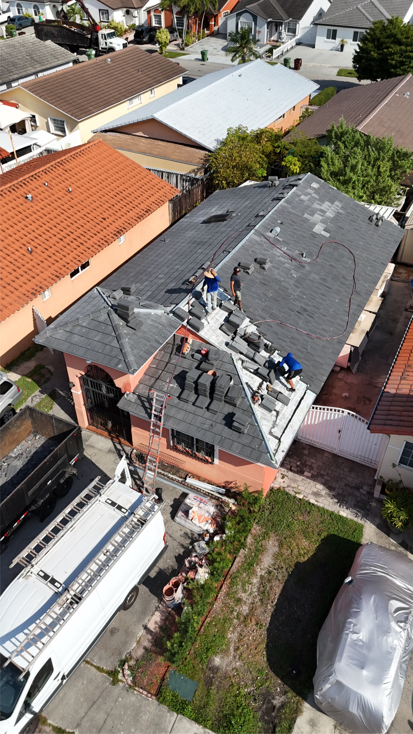 Aerial of old clay tile tear-off in progress with dump truck